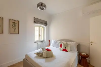 a bedroom with a bed with white sheets and a window at iFlat Trastevere Stylish 4 Bedroom Penthouse in Rome