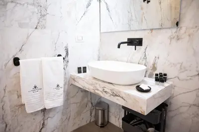 a bathroom with a sink and a marble wall at Domus Laurina - Maison D'Art Collection in Rome