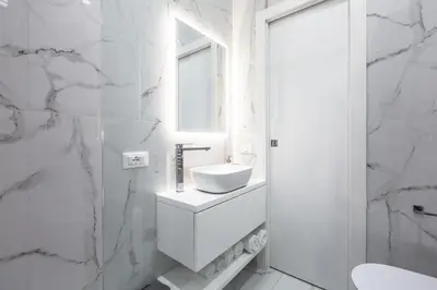 a white bathroom with a sink and a mirror at Alissa Suite in Rome