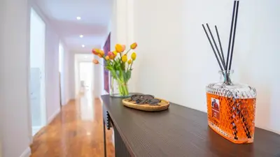 an orange vase sitting on a wooden table with flowers at Domus San Giovanni Elegant Apartment in Rome
