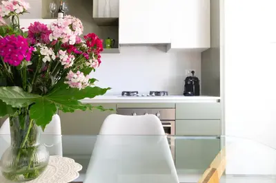 a vase of pink flowers on a table in a kitchen at Apartment near the Vatican Cipro metro station in Rome