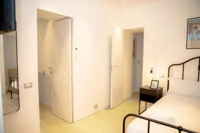a bedroom with white walls and a bed and a mirror at Magikrooms Kandy in Rome