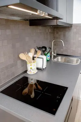 a kitchen counter with a sink and a container of utensils at Magikrooms Kandy in Rome