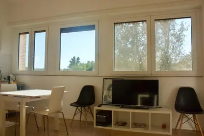 a living room with a table and a tv and three windows at Quadrilatero Flat in Rome