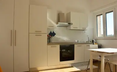 a kitchen with white cabinets and a table at Quadrilatero Flat in Rome