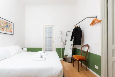 a bedroom with a white bed and a chair at Piazza Cavour Zen Garden-ZEN36 in Rome