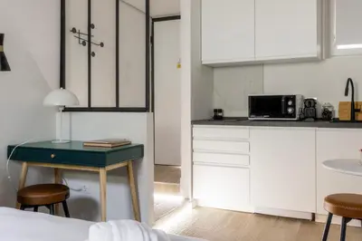 a kitchen with white cabinets and a table with stools at MauveSweetRhome 4 in Rome