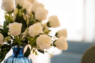 a blue and white vase filled with white roses at Casa Elena - 15 min walk to St Peter's Basilica in Rome