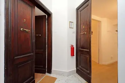 a hallway with two wooden doors and a fire extinguisher at Porta Flaminia Suites in Rome