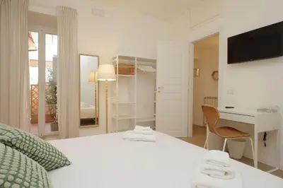 a white bedroom with a bed and a desk at Porta Flaminia Suites in Rome