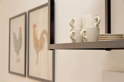 a shelf with two cups and pictures of birds at Porta Flaminia Suites in Rome
