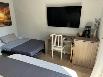 a room with two beds and a desk with a television at Niky House Roma in Rome