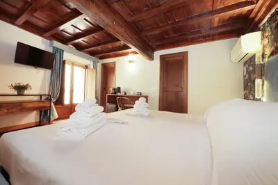 a bedroom with a large white bed with wooden ceilings at Golden Pantheon Rooms in Rome