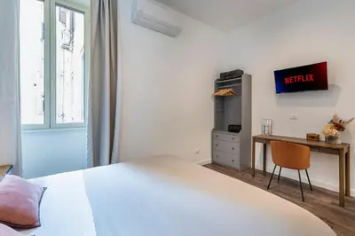 a white bedroom with a bed and a desk at Gracchi boutique rooms in Rome