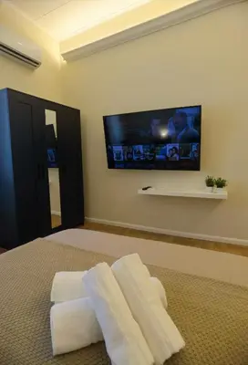 a bedroom with white towels on a bed with a flat screen tv at Metro Lodi Apartment in Rome