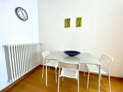 a white table with chairs and a clock on the wall at Vittoria's home in Rome