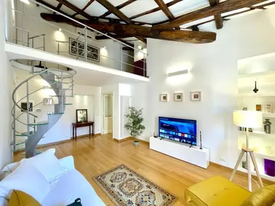 a living room with a spiral staircase and a television at Vittoria's home in Rome