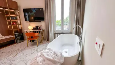 a bathroom with a tub and a table and a window at Vespucci Palace Roma in Rome