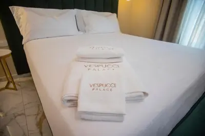 a bed with white towels on the side of it at Vespucci Palace Roma in Rome