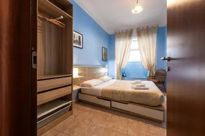 a bedroom with a bed with blue walls and a window at Cipro Tiny House in Rome