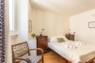 a bedroom with two beds and a chair at iFlat Lovely 2 bedroom apartment in Rione Monti in Rome