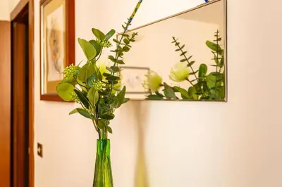 a green vase with flowers in front of a mirror at iFlat Lovely 2 bedroom apartment in Rione Monti in Rome