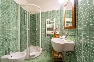 a green tiled bathroom with a sink and a shower at iFlat Lovely 2 bedroom apartment in Rione Monti in Rome