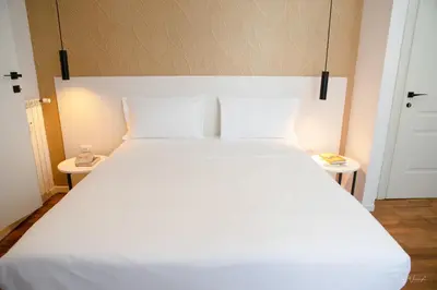 a large white bed in a room with two tables at Magikrooms Topaz in Rome