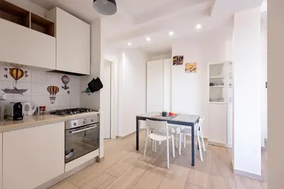 a kitchen with white cabinets and a table and chairs at Ion Apartment in Rome