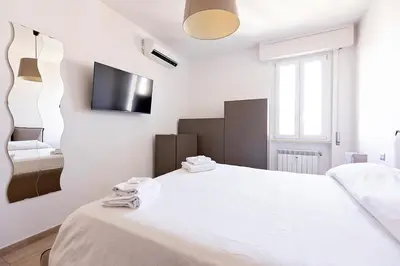 a white bedroom with a bed and a tv on the wall at Ion Apartment in Rome
