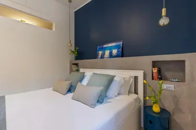 a bedroom with a white bed with blue walls at Brevi Roma Design Apartment in Rome