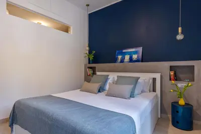 a bedroom with a large white bed with blue walls at Brevi Roma Design Apartment in Rome