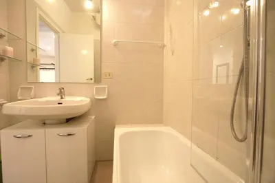 a white bathroom with a sink and a bath tub at Borbera Holiday House in Rome