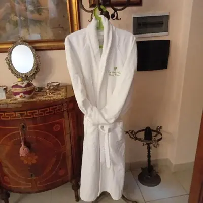 a white robe hanging on a wall next to a mirror at Loft Appia Antica Donna Eugenia in Rome