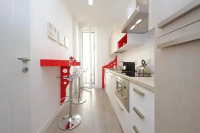 a kitchen with white cabinets and a red shelf at Vatican Claudia's apartment in Rome