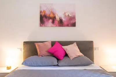 a bed with pink and purple pillows on it at Carpegna Sweet House - A few stops from the city centre in Rome