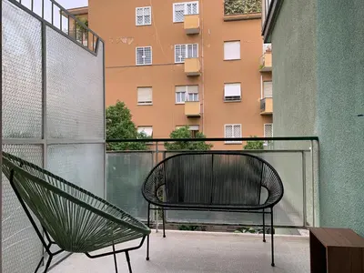 a bench on a balcony with a building at Nox Romana Apartments - Vatican - Modern Apt with Cozy Balcony in Rome