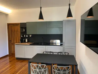 a kitchen with white cabinets and a table with chairs at Nox Romana Apartments - Vatican - Modern Apt with Cozy Balcony in Rome