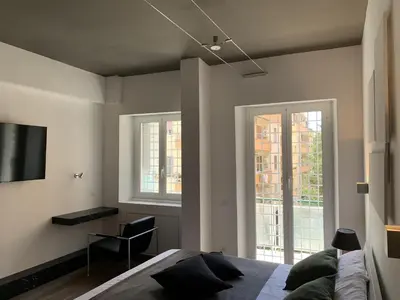 a bedroom with a bed and two windows at Nox Romana Apartments - Vatican - Modern Apt with Cozy Balcony in Rome