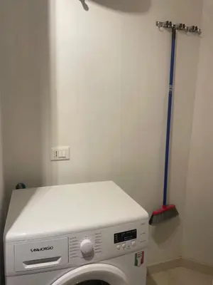 a washing machine in a room with a broom at Chez Margot in Rome