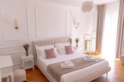 a white bedroom with a bed with two towels on it at The Aristocats Apartment in Rome
