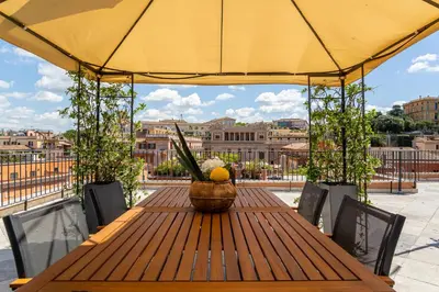 a wooden table with a yellow umbrella on a balcony at iFlat Luxury Penthouse near Trevi Fountain in Rome