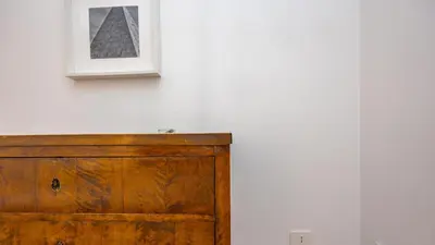 a picture on a white wall next to a wooden dresser at Testaccio's Heart by Rentbeat in Rome