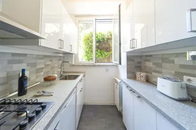a kitchen with white cabinets and a sink and a window at Villino San Cosimato, nel cuore di Trastevere in Rome