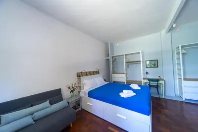 a bedroom with a blue bed and a couch at Villino San Cosimato, nel cuore di Trastevere in Rome