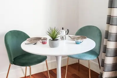 a white table with three green chairs and a plant on it at Splendido appartamento a Villa Ada in Rome