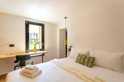 a bedroom with a bed with a desk and a window at iFlat Campo de' Fiori modern apartment in Rome
