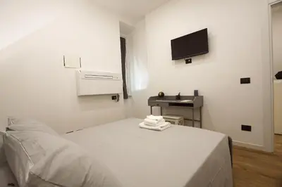 a white room with a bed and a television at Milizie Holiday House in Rome