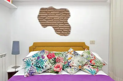 a bed with colorful pillows and a brick wall at Cappellari37 in Rome