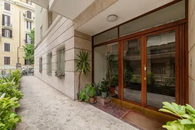 a building with glass doors and potted plants on a sidewalk at GuestHost - Regina Margherita Suite in Rome
